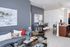 Modern apartment living room with elegant gray tones, stylish decor, and an open kitchen with a breakfast bar.