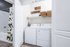 Contemporary laundry room with brand-new washer and dryer, featuring chic shelving and stylish baskets.