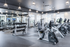 Spacious modern gym featuring state-of-the-art exercise equipment and abundant natural light from large windows.