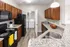 Modern kitchen with sleek appliances, granite countertops, and a convenient laundry area in the background.