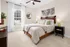 Bright and inviting bedroom with a stylish bed, elegant decor, and a large window with natural light filtering through sheer curtains.