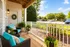 Charming balcony with cozy wicker chairs and vibrant plants, offering a perfect retreat with scenic views of a lush neighborhood.