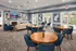 Inviting and modern lounge area featuring elegant round wooden tables, plush blue chairs, and a cozy fireplace, perfect for gatherings.