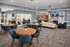 Elegant community lounge with modern blue accents, featuring cozy seating, a fireplace, and a spacious kitchen area.