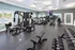 Modern fitness center equipped with state-of-the-art gym machines and free weights, featuring bright natural lighting and a view of the outdoor pool.