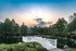 Serene lakeside setting with charming white railing, lush greenery, and twilight skies, perfect for tranquil living.