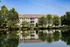 Charming lakeside apartment complex surrounded by lush trees and a tranquil pond, offering serene living and picturesque views.