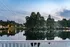 Serene lakeside view with lush greenery and elegant apartment buildings reflecting in calm waters at twilight.