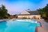 Charming community pool with sparkling blue water, surrounded by cozy lounge chairs and a stylish clubhouse, set under a serene evening sky.