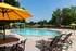 Inviting outdoor pool area with vibrant yellow umbrellas and stylish lounge chairs, surrounded by lush greenery for a perfect relaxation spot.