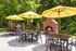 Charming outdoor patio with cozy fireplace, elegant dining tables, and vibrant yellow umbrellas, perfect for relaxed gatherings.