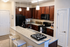 Modern kitchen with elegant granite countertops, rich wooden cabinets, and sleek appliances under warm pendant lighting.