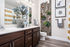 Elegant bathroom with chic wooden cabinetry, stylish wall decor, and plush towels, featuring a modern sink with sleek fixtures.