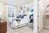 Elegant bedroom with plush bedding, stylish decor, and natural light streaming through large windows, adjacent to a neatly organized walk-in closet.