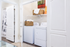 Bright and welcoming laundry area featuring a modern washer and dryer set with stylish wicker baskets for storage.