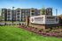 Charming apartment community featuring a grand entrance with manicured gardens and a stylish facade, highlighting Abberly at Southpoint's inviting atmosphere.