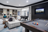 Elegant recreation room featuring a billiards table, foosball, stylish seating, and a built-in office area with modern decor and vibrant lighting.