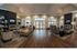 Luxurious living room with elegant hardwood flooring, modern lighting fixtures, and a cozy fireplace. Ample natural light from large windows enhances the spacious, inviting atmosphere.