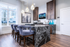 Elegant kitchen with sleek marble island, modern pendant lighting, and plush high-backed stools, featuring large windows for natural light.
