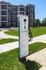 Modern apartment complex with eco-friendly electric vehicle charging station, lush green surroundings, and elegant architectural design.