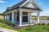 Charming community mail pavilion with classic columns and manicured landscaping under a bright blue sky.