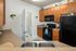 Modern kitchen with warm wooden cabinetry, sleek black appliances, and vibrant decor accents.