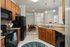 Modern apartment kitchen with sleek black appliances, warm wood cabinetry, and a cozy adjacent dining area.
