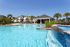 Luxurious apartment complex with a stunning resort-style pool, palm trees, and modern buildings under a clear blue sky.