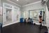 Inviting home fitness room with elegant mirrors, natural lighting, and a wide array of colorful exercise equipment.