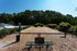 Charming dog park with a spacious fenced area, surrounded by lush greenery and clear blue skies, offering a peaceful retreat for pets and owners alike.