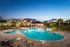 Luxurious apartment complex boasting a stunning outdoor pool area with lush landscaping and inviting seating under a vibrant twilight sky.