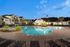 Elegant apartment complex with luxurious pool, surrounded by palm trees and scenic architecture, perfect for modern living.