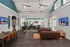 Elegant community lounge featuring high ceilings, modern seating, and multi-functional tables with wall-mounted TVs for entertainment.