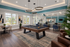 Luxurious community lounge featuring a stylish pool table, modern seating, and computer stations with vibrant decor and ample natural light.