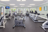 Modern fitness center with state-of-the-art equipment, including treadmills, stationary bikes, and strength-training machines, illuminated by natural light and motivational decor.