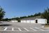 Modern apartment complex with spacious garages set against a backdrop of lush greenery and a clear blue sky.