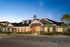 Charming brick building with elegant architectural details surrounded by lush landscaping and sunset skies.