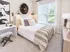 Bright and inviting bedroom with elegant decor, featuring a plush bed, stylish wall art, and large sunny window.