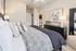 Elegant bedroom featuring a plush, patterned bedspread, decorative pillows, and modern furnishings in a bright and inviting space.