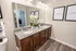 Elegant bathroom with dual sinks, granite countertop, and stylish decor, featuring modern wood cabinetry and vibrant wall art.