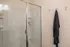 Modern bathroom featuring a sleek shower with glass doors, elegant wall hooks, and plush robe for a luxurious touch.