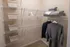 Spacious walk-in closet with organized wire shelving, stylish wicker baskets, and neatly hung clothing, offering ample storage solutions.
