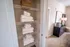 Charming apartment linen closet with neatly stacked fresh white towels beside a cozy bedroom, featuring elegant decor and a stylish dresser.