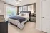 Inviting bedroom with chic decor, featuring a cozy bed, stylish artwork, and abundant natural light through large windows.