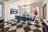 Chic and modern conference room featuring a stylish table with six blue chairs, elegant wall art, and a large TV displaying a morning show, creating an inviting atmosphere.