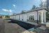 Charming row of modern garages with elegant white doors, surrounded by lush green trees and a clear blue sky.