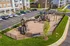 Vibrant apartment community playground surrounded by lush greenery, featuring modern play structures and ample seating.