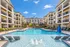 Luxurious apartment complex with resort-style swimming pool, surrounded by modern multi-story buildings under a clear blue sky.