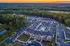 Aerial view of a luxurious apartment complex at sunset, featuring landscaped grounds and a central pool area surrounded by modern architecture, nestled amid lush greenery.