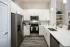 Apartment kitchen with white cabinetry, stainless steel appliances, and quartz countertops at Abberly Royal Creek in Raleigh, NC.